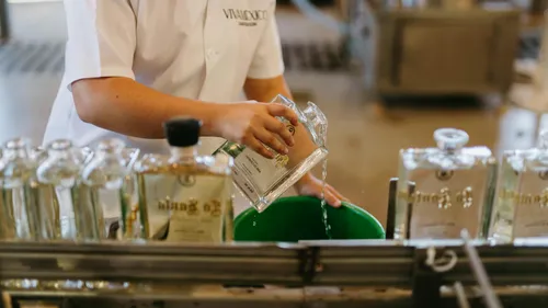 Person pouring clear liquid into green bucket.