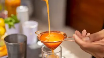Orangensaft wird ins Glas gefiltert.