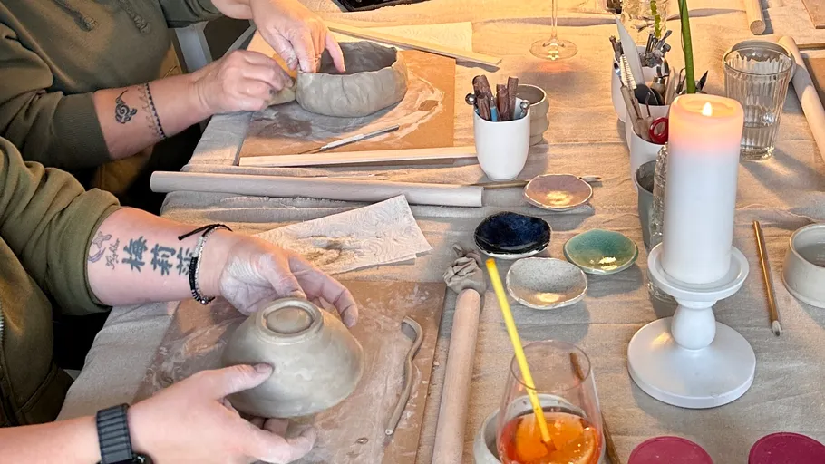 People crafting pottery on a table.