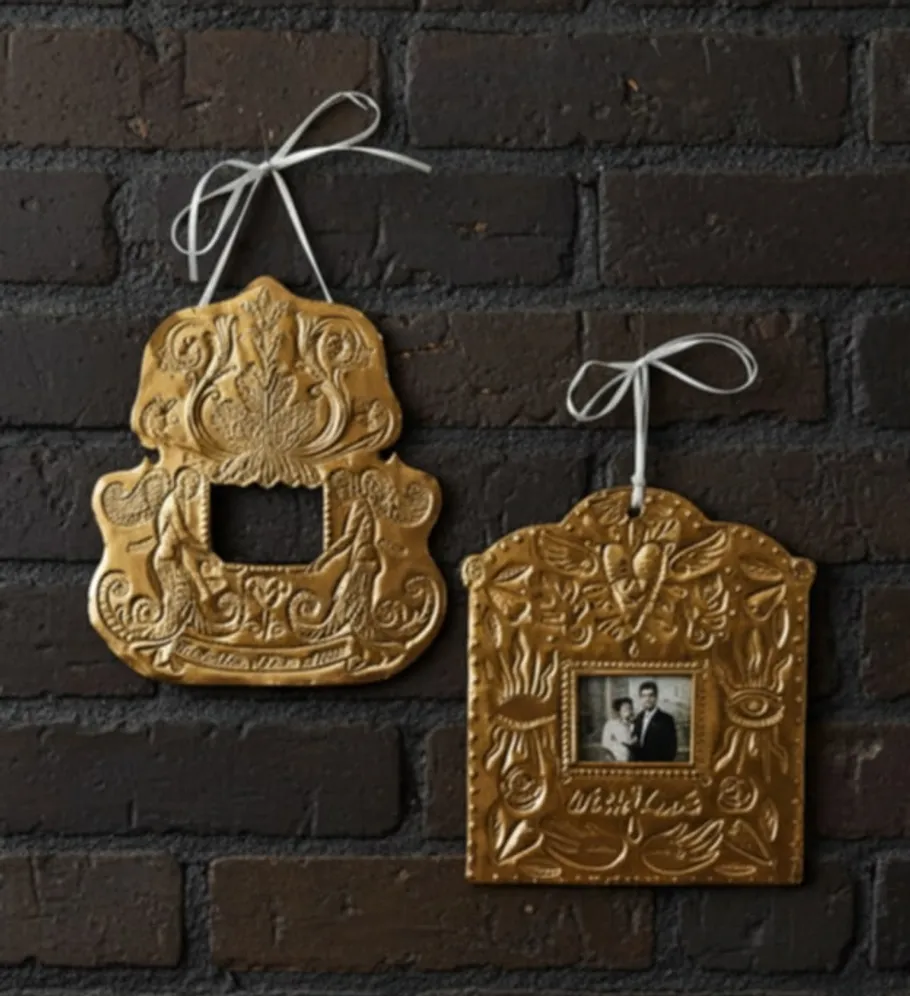 Two ornate, gold frames hanging on brick wall.