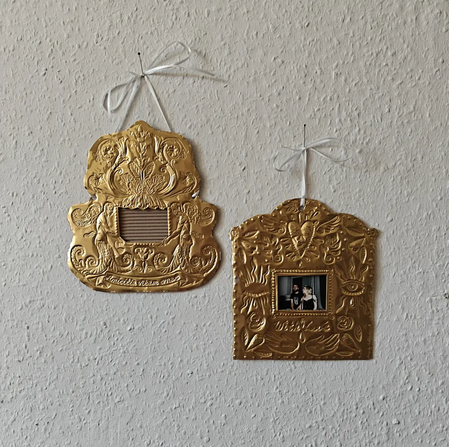 Two gold decorative frames hanging on a wall.