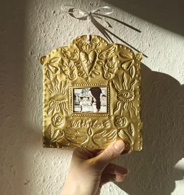 Hand holds ornate gold picture frame.
