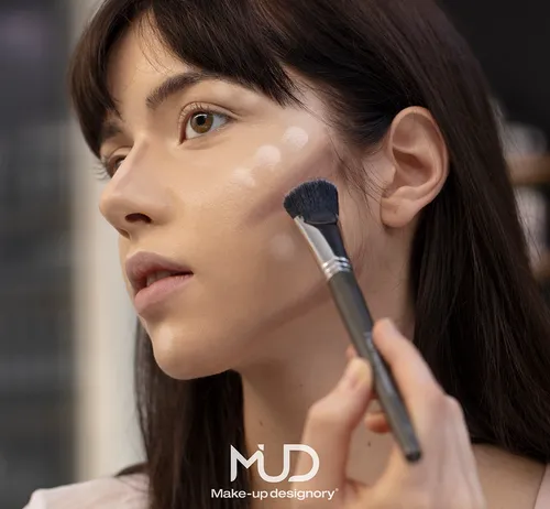 Woman applying makeup on her cheek.