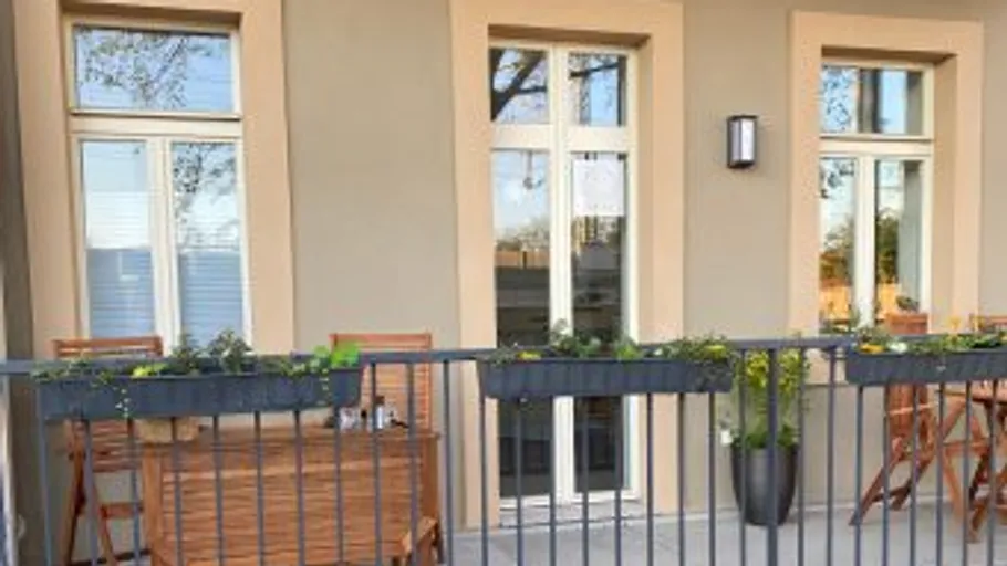 Balcony with chairs, table, and planters.