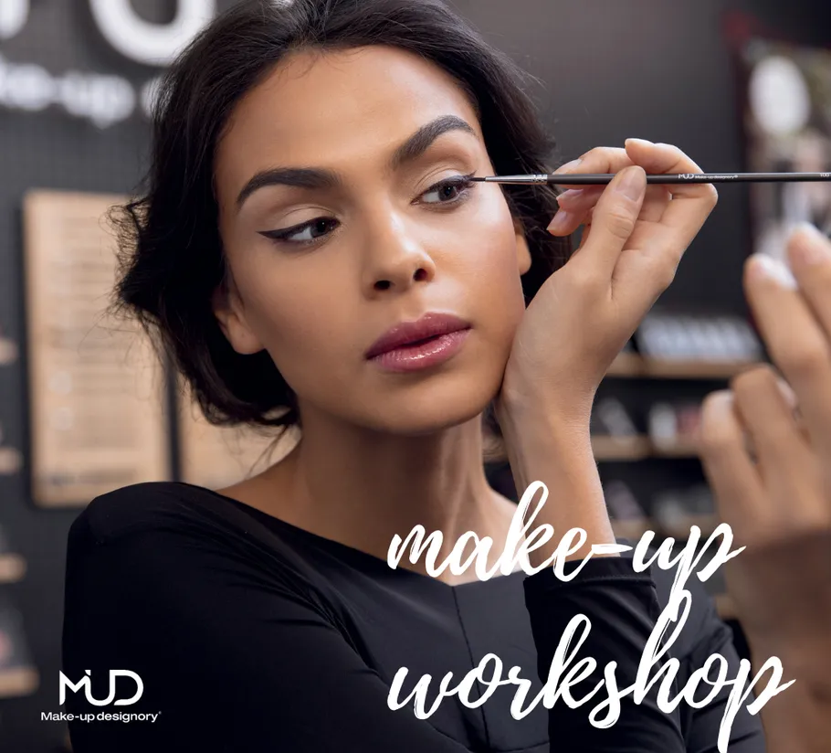 Woman applying makeup with brush in workshop.