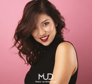 Smiling woman poses against pink background.