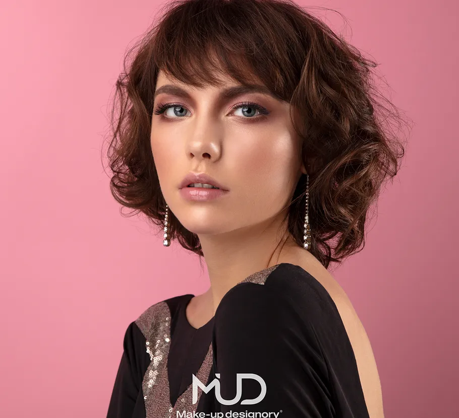 Woman with earrings against pink background.