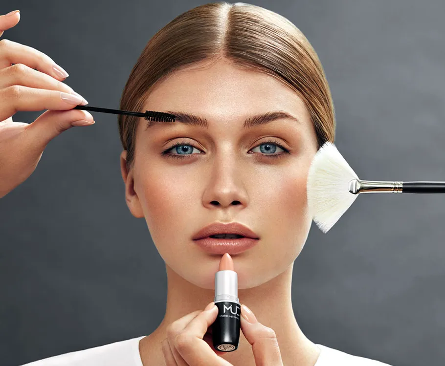 Woman receiving makeup application with lipstick.