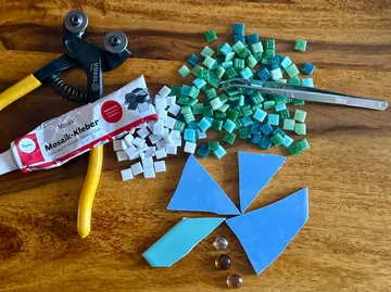 Mosaikwerkzeuge, Fliesen und Kleber auf Holzoberfläche.