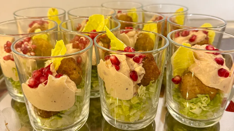 Appetizers in glasses with sauce and pomegranate seeds.