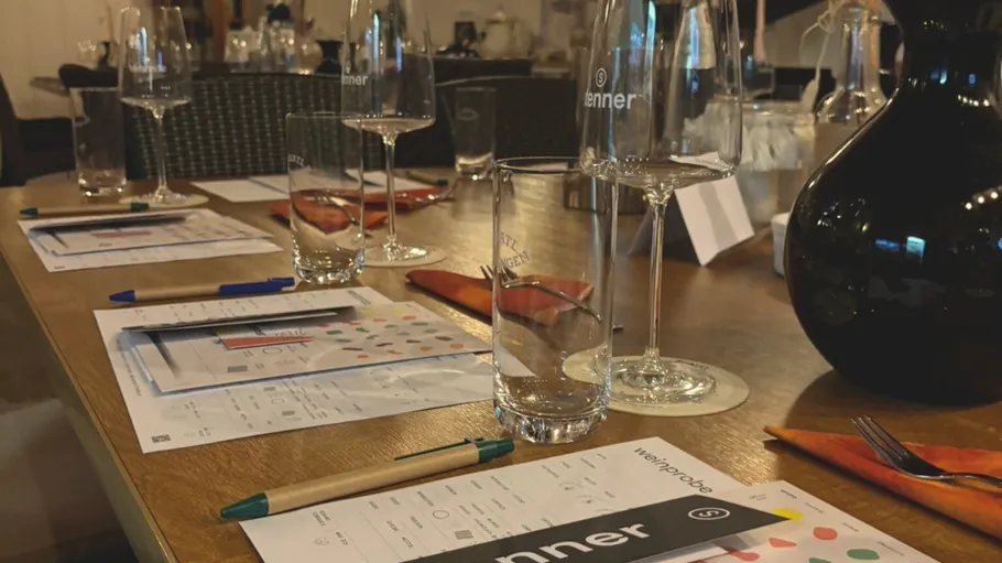 Weinprobe-Tisch mit Gläsern, Papieren und Stiften.