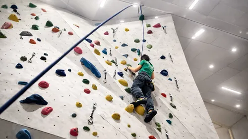 Person climbing indoor rock wall, colorful grips.