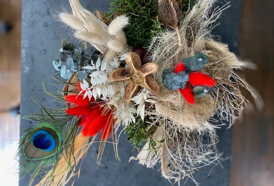 Buntes Trockenblumengesteck auf dunkler Oberfläche.