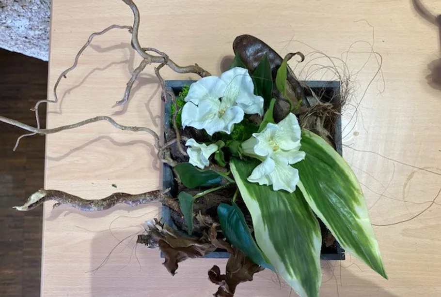 Blumengesteck mit weißen Blumen auf Tisch.