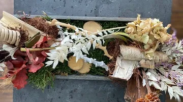 Floral arrangement with leaves on stone surface.