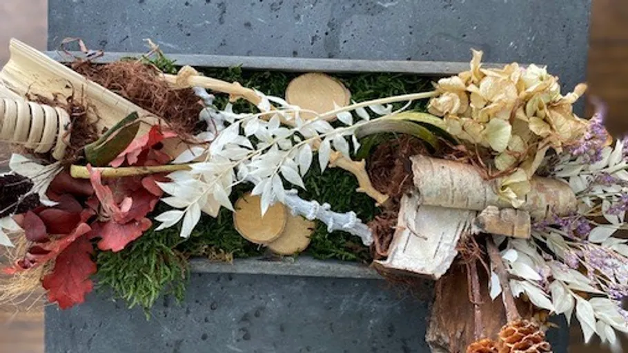 Blumenarrangement mit Blättern auf Steinoberfläche.