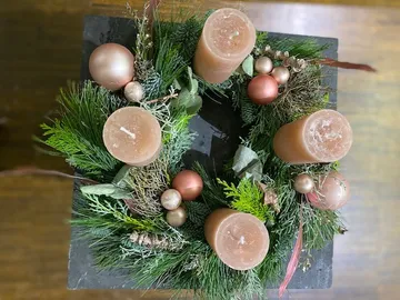 Candle wreath with pink ornaments and greenery.