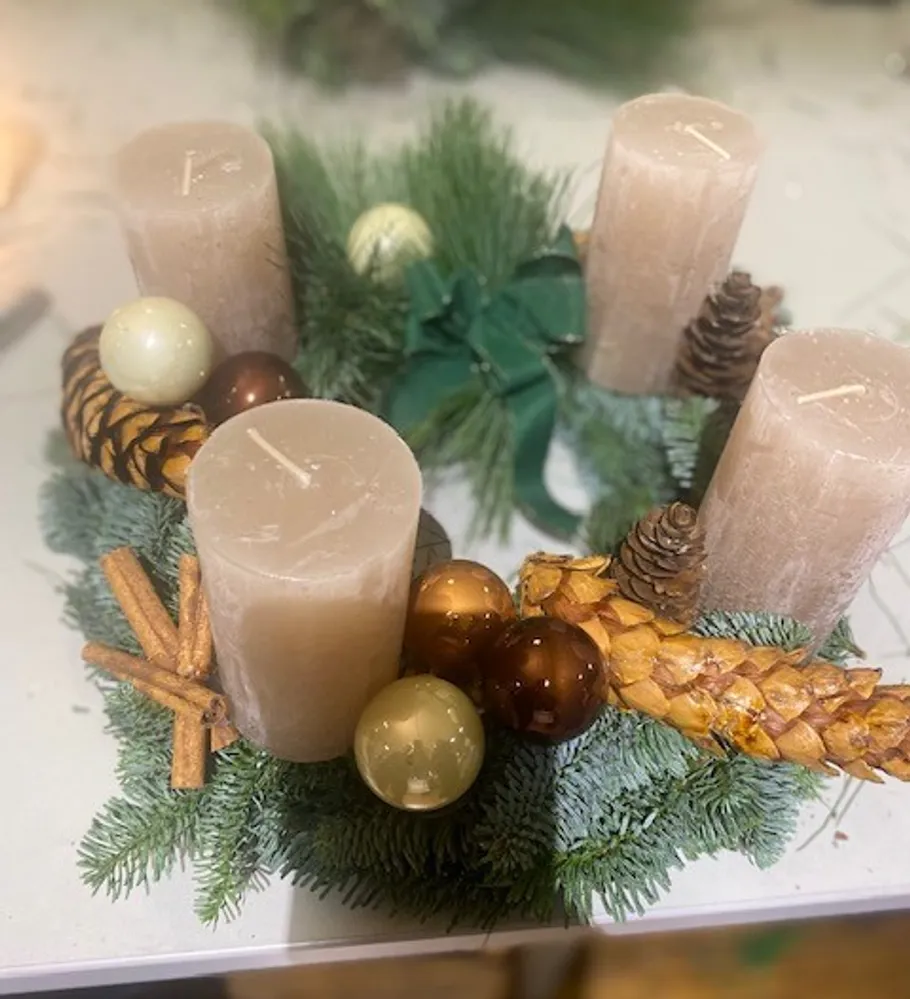 Advent wreath with candles, pinecones, and ornaments.