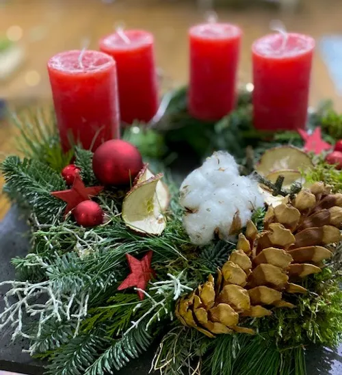 Four red candles on Christmas wreath decoration.