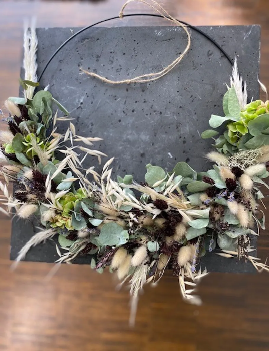 Floral wreath with greenery on a slate background.