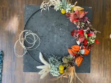 Decorative autumn wreath with colorful leaves on table.