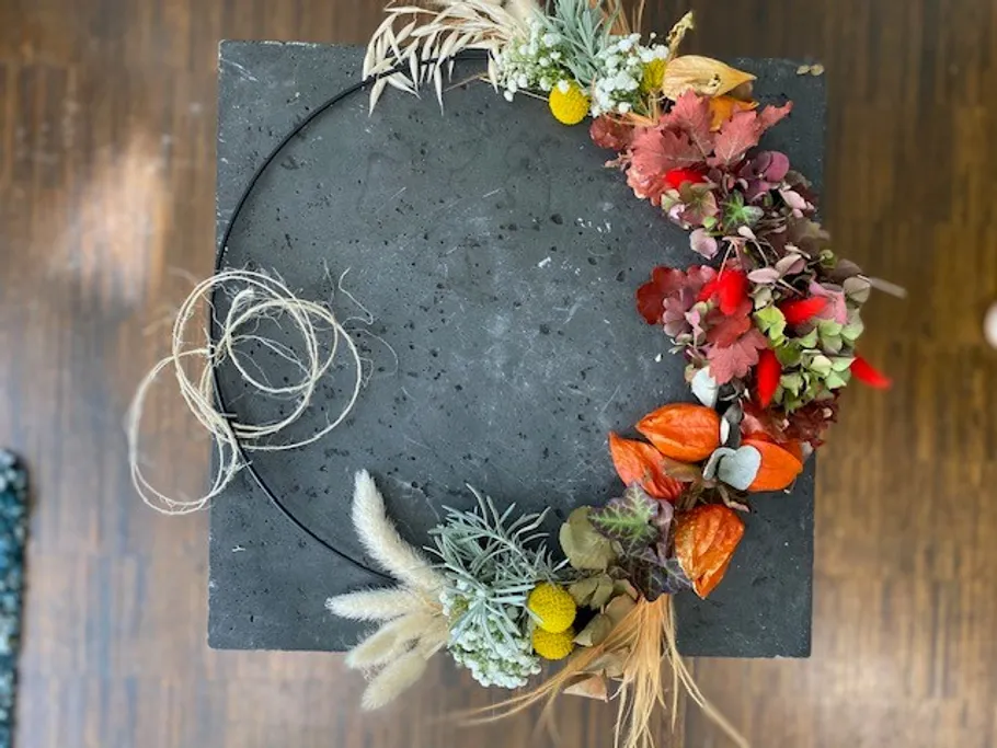 Herbstlicher Dekokranz mit bunten Blättern auf Tisch.