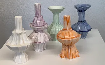 Bunte, geometrische Keramikkrüge auf einem Tisch.