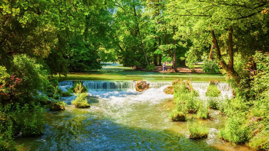 Small waterfall flowing in lush green park.