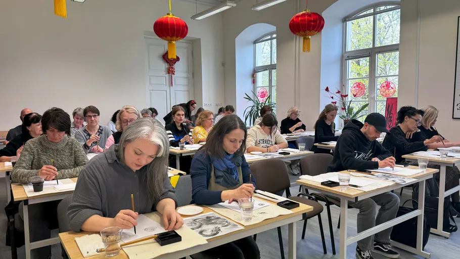 People painting in classroom with red lanterns.
