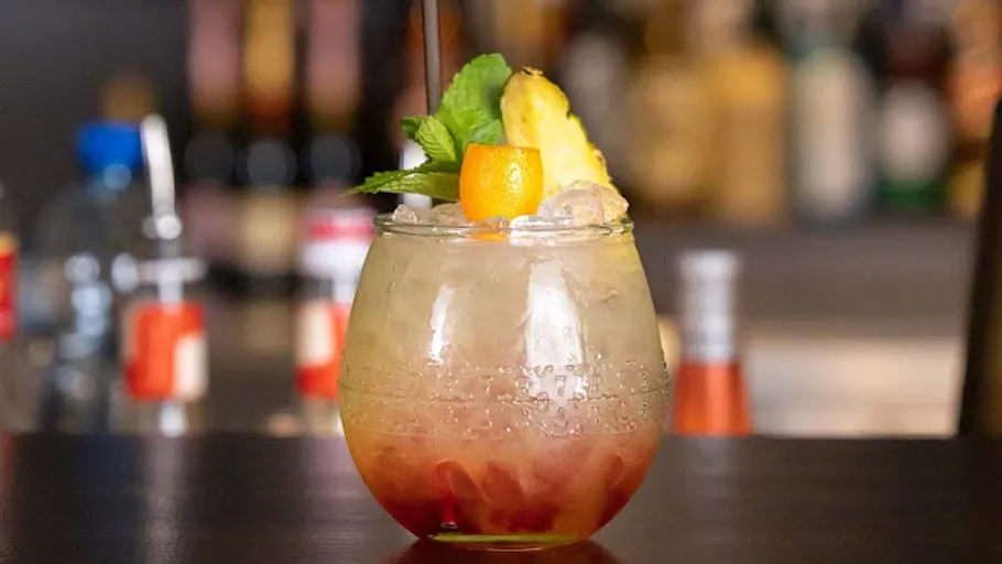 Bunter Cocktail mit Fruchtgarnitur auf Bar.