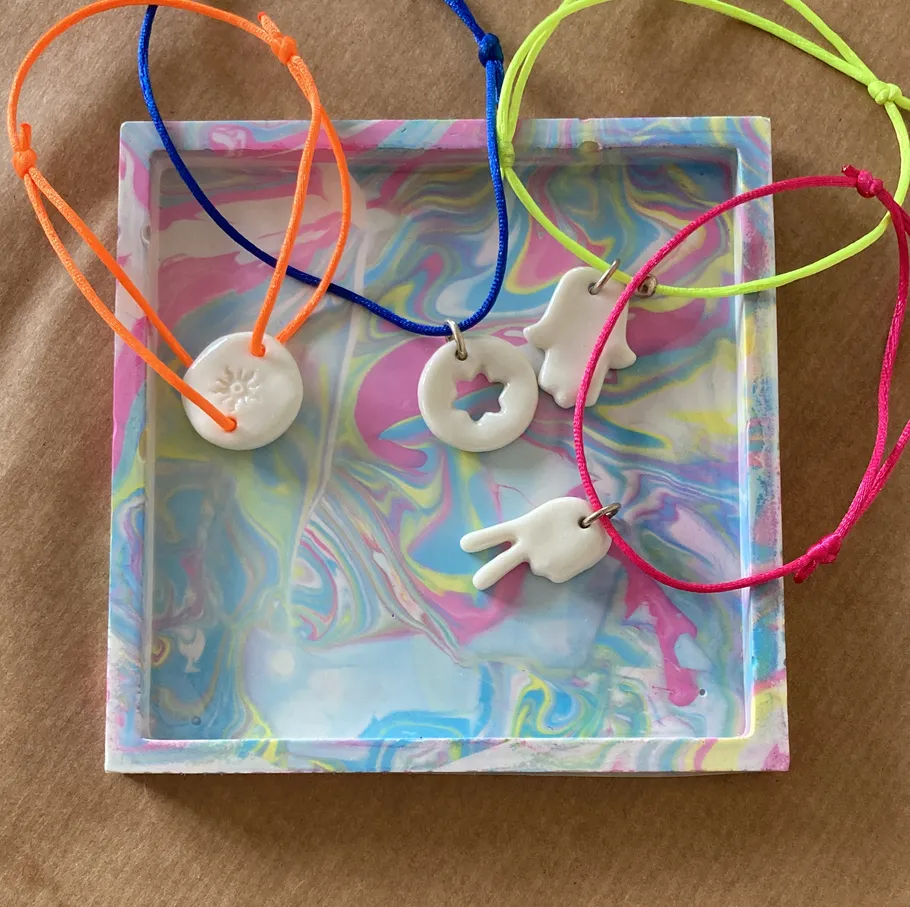 Colorful bracelets with charms on marbled tray.