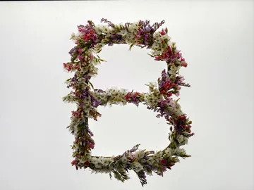 Blumenbuchstabe B auf schlichtem Hintergrund.