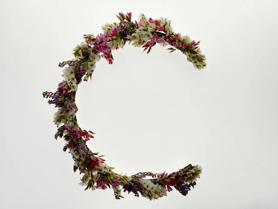 Flower wreath forming letter C, white background.