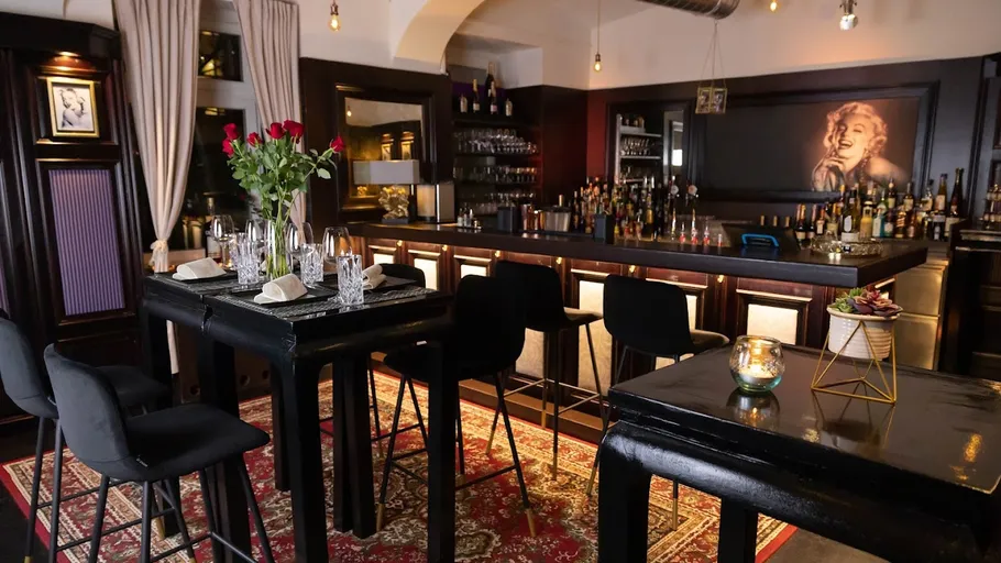 Elegante Bar mit Hochtischen und Bild.