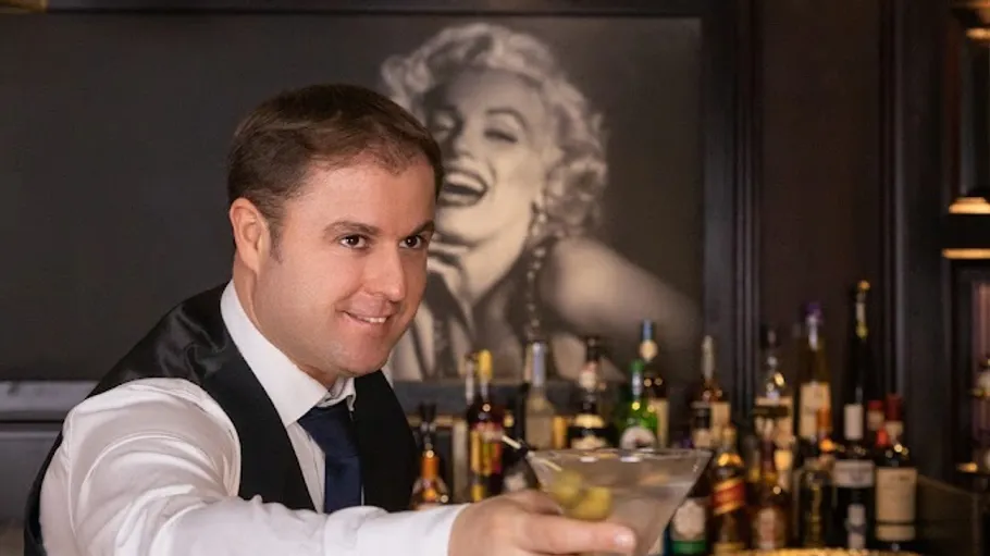 Bartender serving martini in elegant bar.