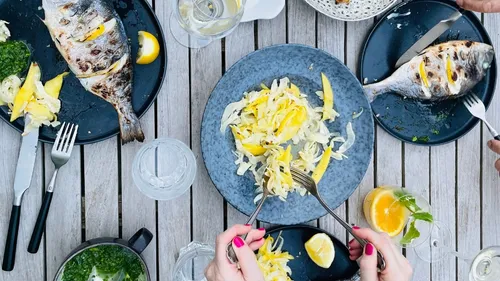 Grilled fish and salad on wooden table.