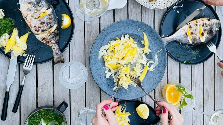 Grilled fish and salad on wooden table.