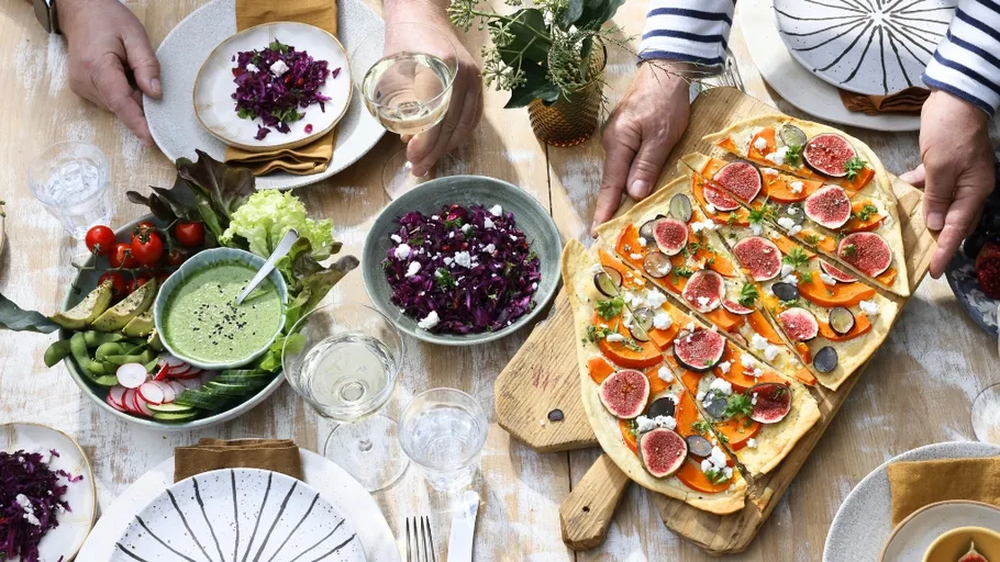 People sharing colorful food on wooden table.