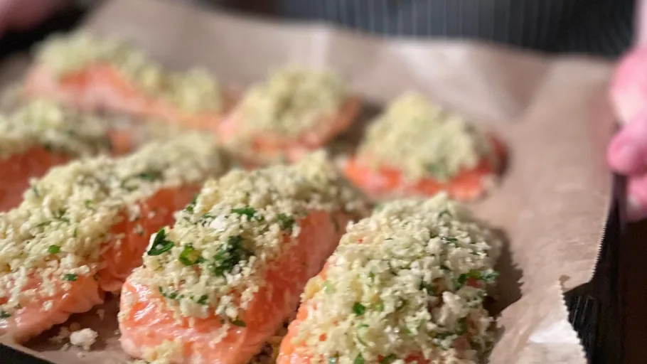 Salmon fillets with herb crust on tray.