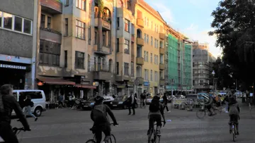 Menschen radeln auf städtischer Straße mit Gebäuden.