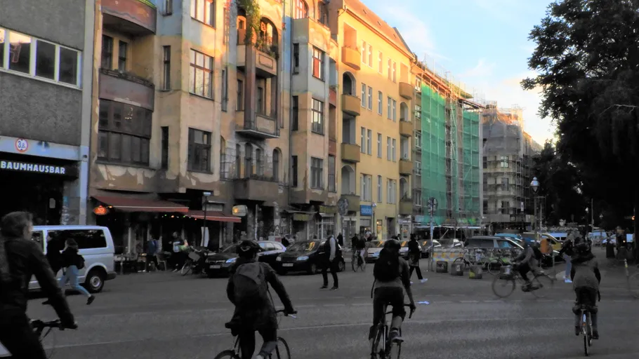 Menschen radeln auf städtischer Straße mit Gebäuden.