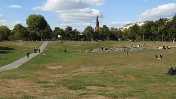 Leute entspannen sich in einem großen, grünen Park.