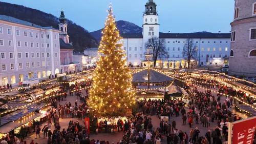 Large Christmas market with illuminated tree at dusk.