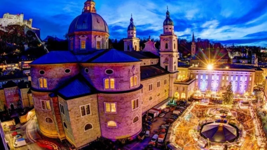 Illuminated cathedral near festive nighttime market.