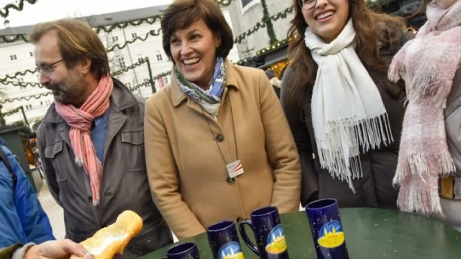 Gruppe genießt Weihnachtsmarkt mit Tassen.