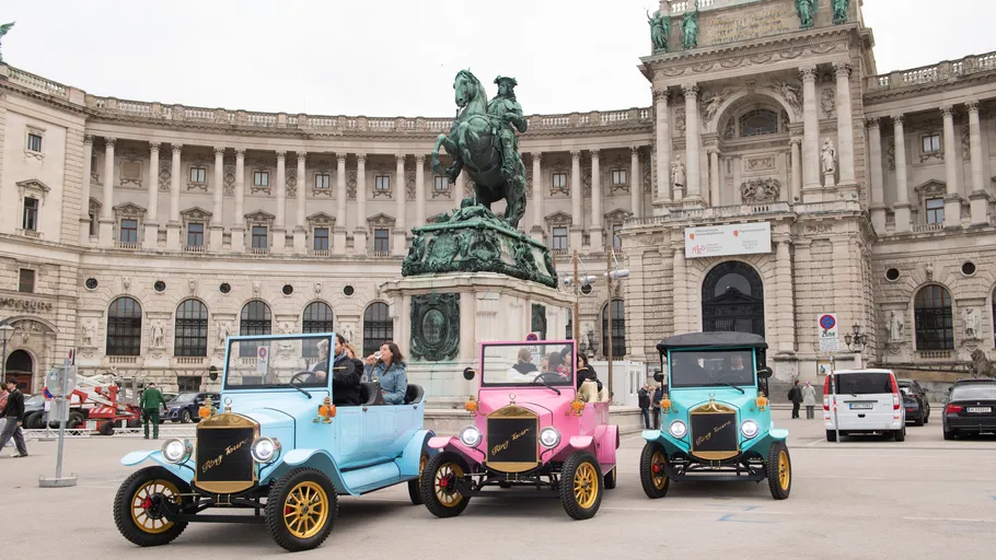 Three vintage cars parked near historic building.