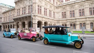 Oldtimer fahren nahe historischem Gebäude.