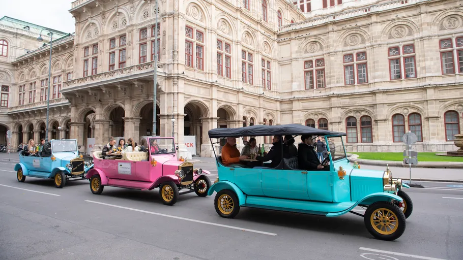 Vintage cars driving near historic building.
