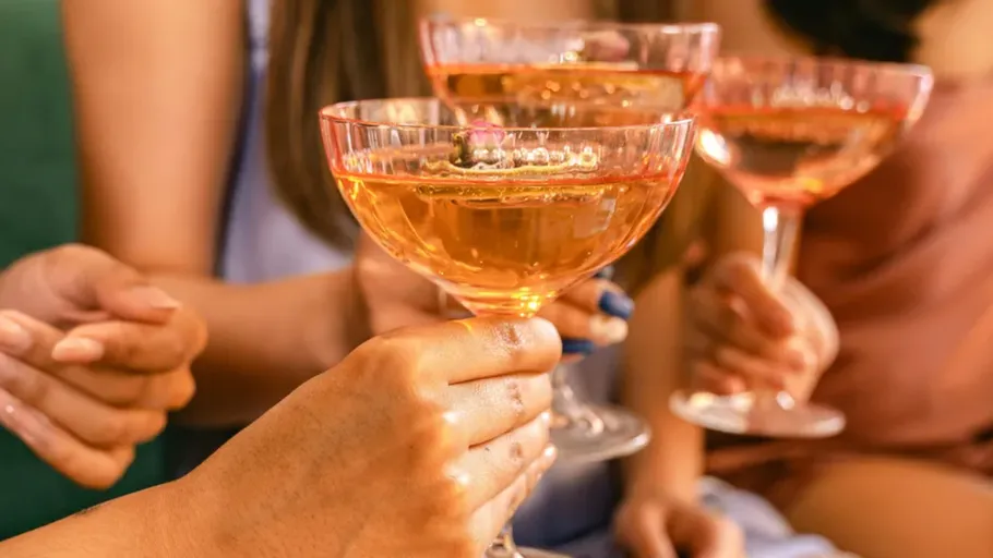 Hands holding champagne glasses, celebratory setting.