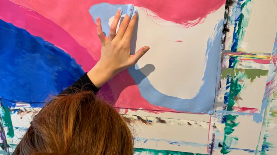 Hand painting blue on colorful canvas.